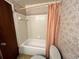 Cozy bathroom with tub and shower, patterned wallpaper, and toilet at 405 S Shore Dr, Eagle Lake, FL 33839
