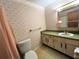 Compact bathroom with vintage-style wallpaper, vanity, and shower/tub combo at 405 S Shore Dr, Eagle Lake, FL 33839