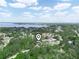 An aerial view of a neighborhood by a body of water, with homes surrounded by lush trees on a sunny day. Pinned Location at 509 Mountain Dr, Babson Park, FL 33827
