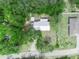Aerial view of a house surrounded by a verdant, tree-filled yard, showcasing its metal roof and proximity to neighboring homes at 509 Mountain Dr, Babson Park, FL 33827