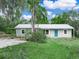 Charming single story home featuring a metal roof, blue door, mature landscaping, and a lush green lawn at 509 Mountain Dr, Babson Park, FL 33827