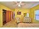 Spacious bedroom featuring yellow walls, carpet, ceiling fan, double closet, and vintage decor at 509 N Scenic Hwy, Frostproof, FL 33843