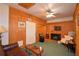 Living room with wood walls, carpet floors, comfortable seating, tv and a ceiling fan at 509 N Scenic Hwy, Frostproof, FL 33843