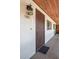 Close-up of an entryway to a condo with a sturdy wood door, decorative light fixture, and brick flooring at 6201 Country Club Dr # 21, Lake Wales, FL 33898