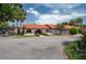 Community building with a red tiled roof, manicured landscaping, and a circle driveway on a sunny day at 6201 Country Club Dr # 21, Lake Wales, FL 33898
