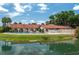 A community pool and pool house overlooking the water on a sunny day with blue sky and fluffy clouds at 6201 Country Club Dr # 21, Lake Wales, FL 33898