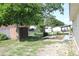 Backyard view showing a lawn with mature trees, an outdoor table with a lounge, shed, and fence at 7 Lamplight Ln, Winter Haven, FL 33884