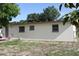 The backyard shows a simple lawn and exterior wall with three windows in a peaceful residential setting at 7 Lamplight Ln, Winter Haven, FL 33884