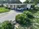 Lush front yard with flowering bushes leads to a covered carport of this single-story home at 7 Lamplight Ln, Winter Haven, FL 33884