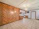 Open-concept kitchen with white tile floors, wood paneled walls and view into the kitchen at 715 S Seminole Ave, Fort Meade, FL 33841
