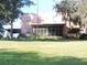 View of a backyard with a covered patio, lush green lawn, and mature trees in the distance at 7254 Wisteria Ln, Lake Wales, FL 33898