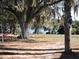 Large backyard with mature trees, a playground, and glimpses of the lake in the distance at 7254 Wisteria Ln, Lake Wales, FL 33898