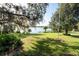 Expansive backyard with lush lawn, mature trees, and lake views at 7254 Wisteria Ln, Lake Wales, FL 33898