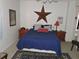Comfortable bedroom with a blue comforter and rustic decor, featuring a large decorative star on the wall at 7254 Wisteria Ln, Lake Wales, FL 33898