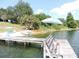 Picturesque view from a wooden dock featuring chairs, boats, and a lush shoreline at 7254 Wisteria Ln, Lake Wales, FL 33898