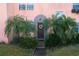 Charming home entrance with arched detail, surrounded by lush greenery and mature palm trees at 7254 Wisteria Ln, Lake Wales, FL 33898