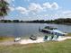 Scenic view of a peaceful lake with a dock, lounge chairs, and a sandy beach area at 7254 Wisteria Ln, Lake Wales, FL 33898