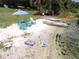 Relaxing lakeside beach with chairs, umbrella, and a boat ready for enjoying the water at 7254 Wisteria Ln, Lake Wales, FL 33898