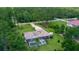 Aerial view of a home with a screened pool in a lush, green, treed community with a long driveway at 7591 Limonia Dr, Indian Lake Estates, FL 33855