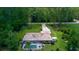 Aerial view of a home with a screened pool and long driveway in a lush, green, treed community at 7591 Limonia Dr, Indian Lake Estates, FL 33855