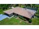 Aerial view of the home with a tile roof, screened-in pool, and lush landscaping at 7591 Limonia Dr, Indian Lake Estates, FL 33855