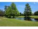 Backyard features a large pond with mature shade trees at 7591 Limonia Dr, Indian Lake Estates, FL 33855