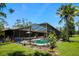 Spacious backyard with a screened pool enclosure and tropical landscaping at 7591 Limonia Dr, Indian Lake Estates, FL 33855