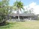 A backyard view shows a screened pool and patio surrounded by lush landscaping and lawn at 7591 Limonia Dr, Indian Lake Estates, FL 33855