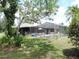 A backyard view shows a screened pool and patio surrounded by lush landscaping and lawn at 7591 Limonia Dr, Indian Lake Estates, FL 33855