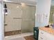 Bathroom featuring glass shower door, handrails, tiling and storage at 7591 Limonia Dr, Indian Lake Estates, FL 33855