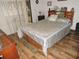 Bedroom with wooden floors, bed with storage, and warm lighting from bedside lamp at 7591 Limonia Dr, Indian Lake Estates, FL 33855