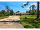 Charming single-story home featuring a lush green lawn, mature trees, and a long private driveway at 7591 Limonia Dr, Indian Lake Estates, FL 33855