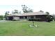 Exterior featuring mature landscaping, stone accents, and a well-maintained lawn at 7591 Limonia Dr, Indian Lake Estates, FL 33855