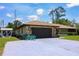Attractive ranch style home with stone accents, a two-car garage, and a spacious driveway at 7591 Limonia Dr, Indian Lake Estates, FL 33855