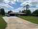 Well-maintained single-story home with a long driveway and mature landscaping at 7591 Limonia Dr, Indian Lake Estates, FL 33855