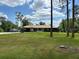 Single-story home with a well-manicured lawn and mature trees, offering a serene setting at 7591 Limonia Dr, Indian Lake Estates, FL 33855