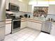 Well-lit kitchen with a stainless steel refrigerator, stove, dishwasher, and overhead cabinets at 7591 Limonia Dr, Indian Lake Estates, FL 33855