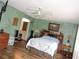Comfortable bedroom with wood flooring, a ceiling fan, and an ensuite bathroom at 7591 Limonia Dr, Indian Lake Estates, FL 33855