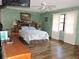 Cozy bedroom with wood flooring, ceiling fan, and a large window providing natural light at 7591 Limonia Dr, Indian Lake Estates, FL 33855