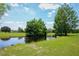 Scenic view of the pond with mature trees on a bright, sunny day at 7591 Limonia Dr, Indian Lake Estates, FL 33855