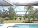 A screened-in pool with a lush golf course view is perfect for outdoor enjoyment at 7591 Limonia Dr, Indian Lake Estates, FL 33855