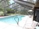 A screened-in pool with a patio and landscaped yard is perfect for outdoor living at 7591 Limonia Dr, Indian Lake Estates, FL 33855