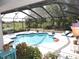 A screened in backyard oasis featuring a pool, lounge chairs and lush greenery at 882 Redwood Way, Lake Wales, FL 33898