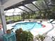 A screened in backyard oasis featuring a pool, lounge chairs and lush greenery at 882 Redwood Way, Lake Wales, FL 33898