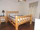 Cozy bedroom with wood-style flooring, a rustic bed frame, and an end table at 9365 Lemon Dr, Lake Wales, FL 33898