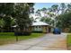 Ranch-style home features a long driveway leading to an attached garage, surrounded by green lawns and mature trees at 9365 Lemon Dr, Lake Wales, FL 33898