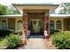 Charming covered porch with rocking chairs framed by stone pillars and lush landscaping create a warm and welcoming entrance at 9365 Lemon Dr, Lake Wales, FL 33898