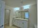 Bathroom with dual sinks, white cabinets, large mirror and modern lighting at 1417 Leamington Ln, Winter Haven, FL 33884