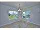 Bright dining area featuring tile floors, elegant chandelier, and large windows with backyard views at 1417 Leamington Ln, Winter Haven, FL 33884