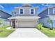 Two-story home with a two-car garage, tan siding, white shutters, and well manicured lawn and landscaping at 1417 Leamington Ln, Winter Haven, FL 33884